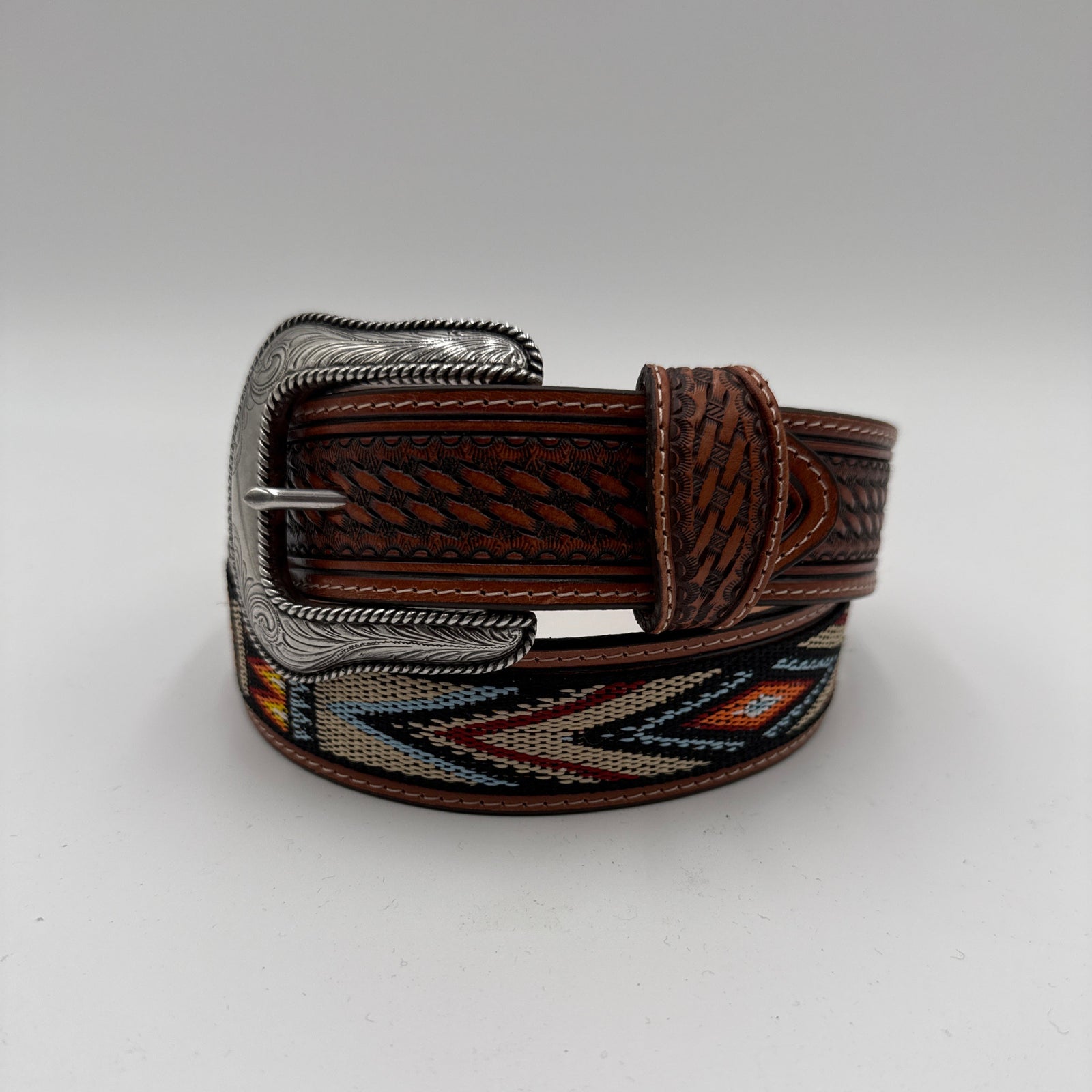 Brown leather belt with decorative buckle on a light gray background