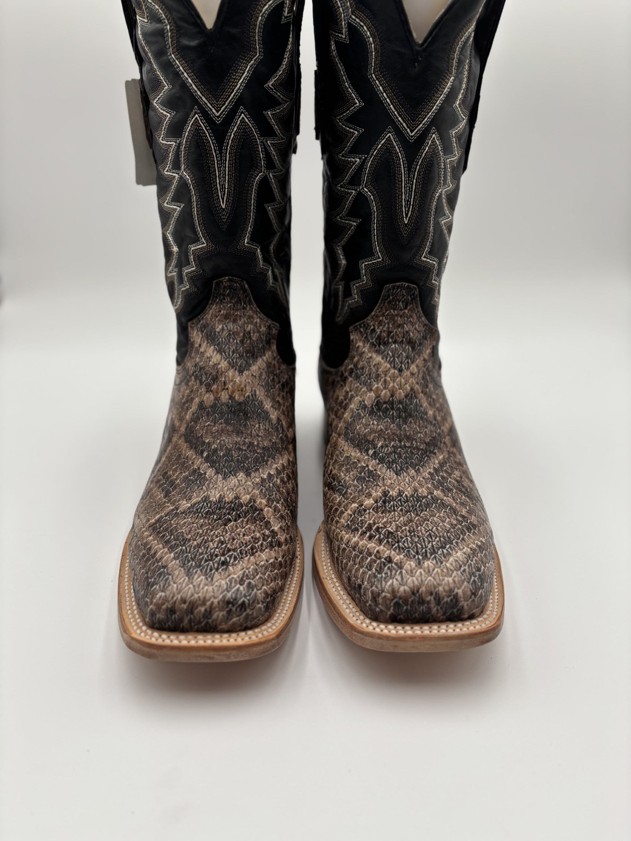 Pair of cowboy boots with black and brown snake skin pattern on a white background