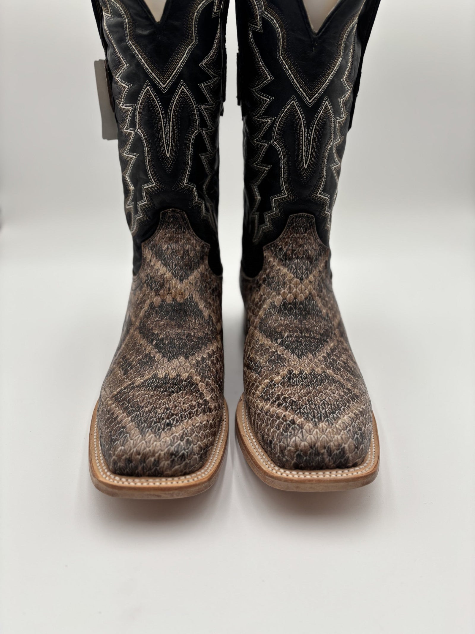 Pair of cowboy boots with black and brown snake skin pattern on a white background