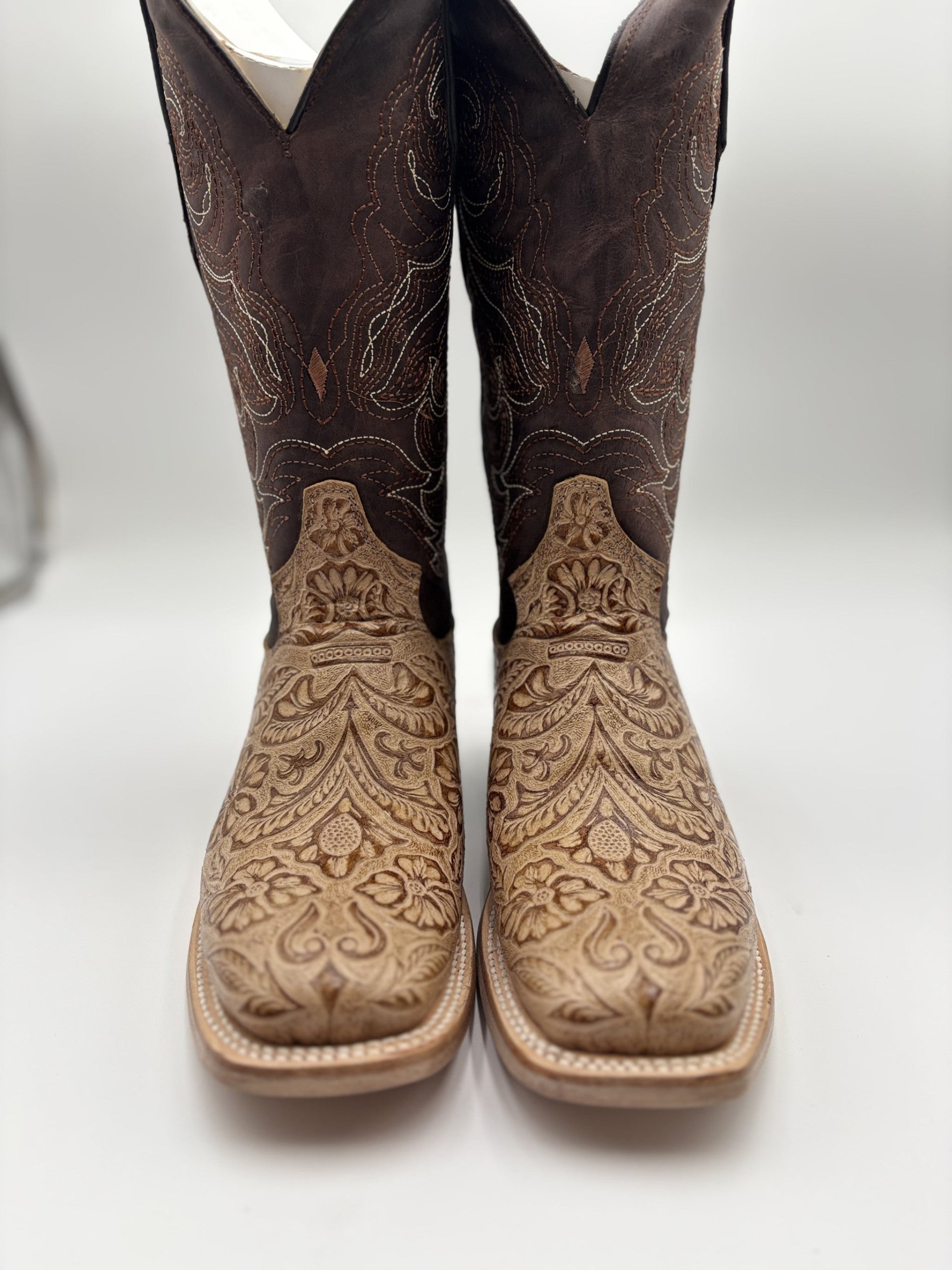Pair of brown cowboy boots with intricate embossing on a white background