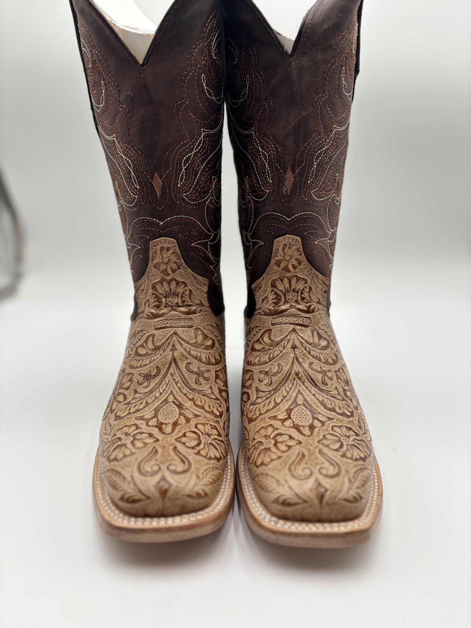 Pair of brown cowboy boots with intricate embossing on a white background