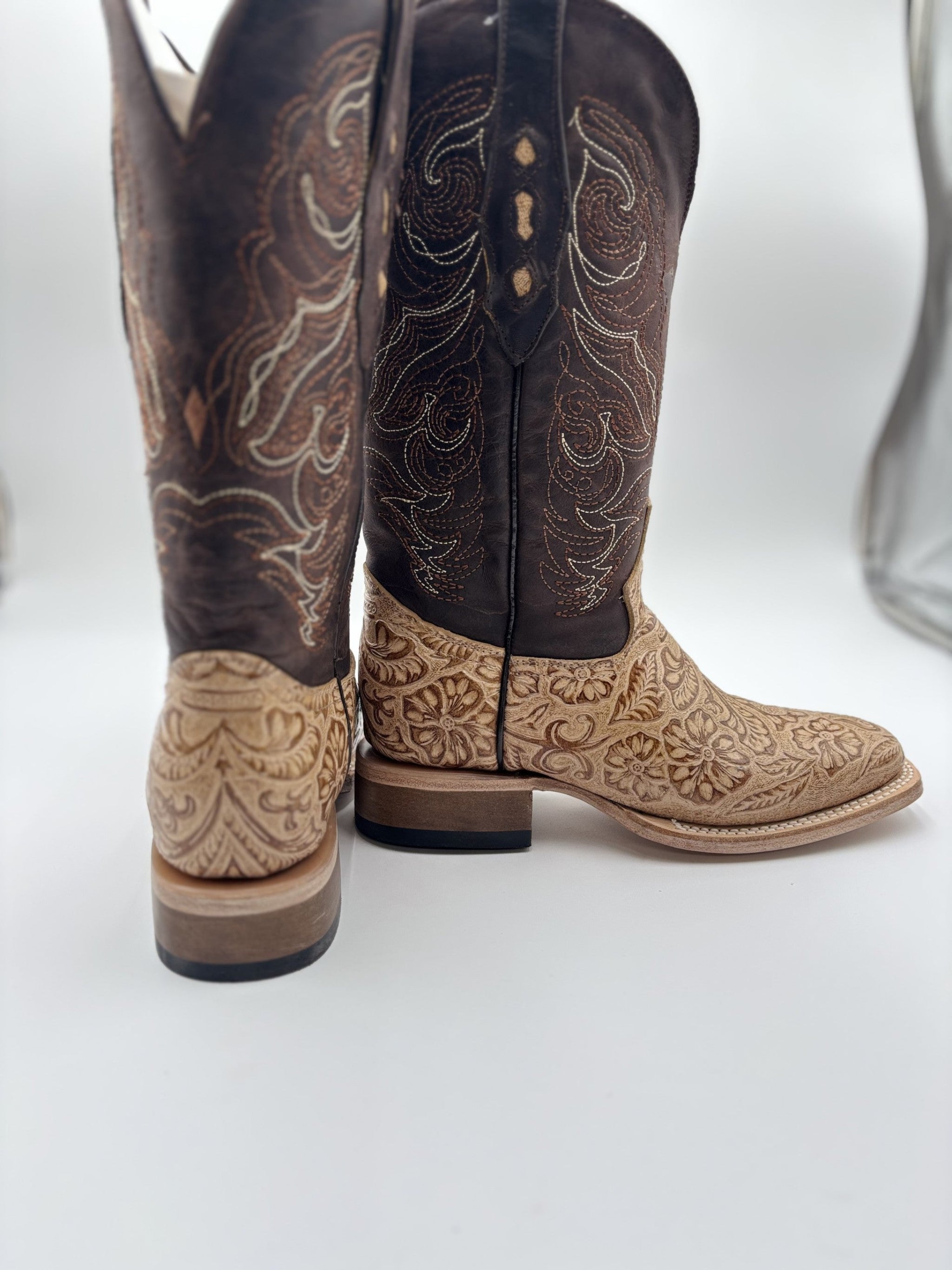 Pair of brown and beige cowboy boots with intricate patterns on a white background