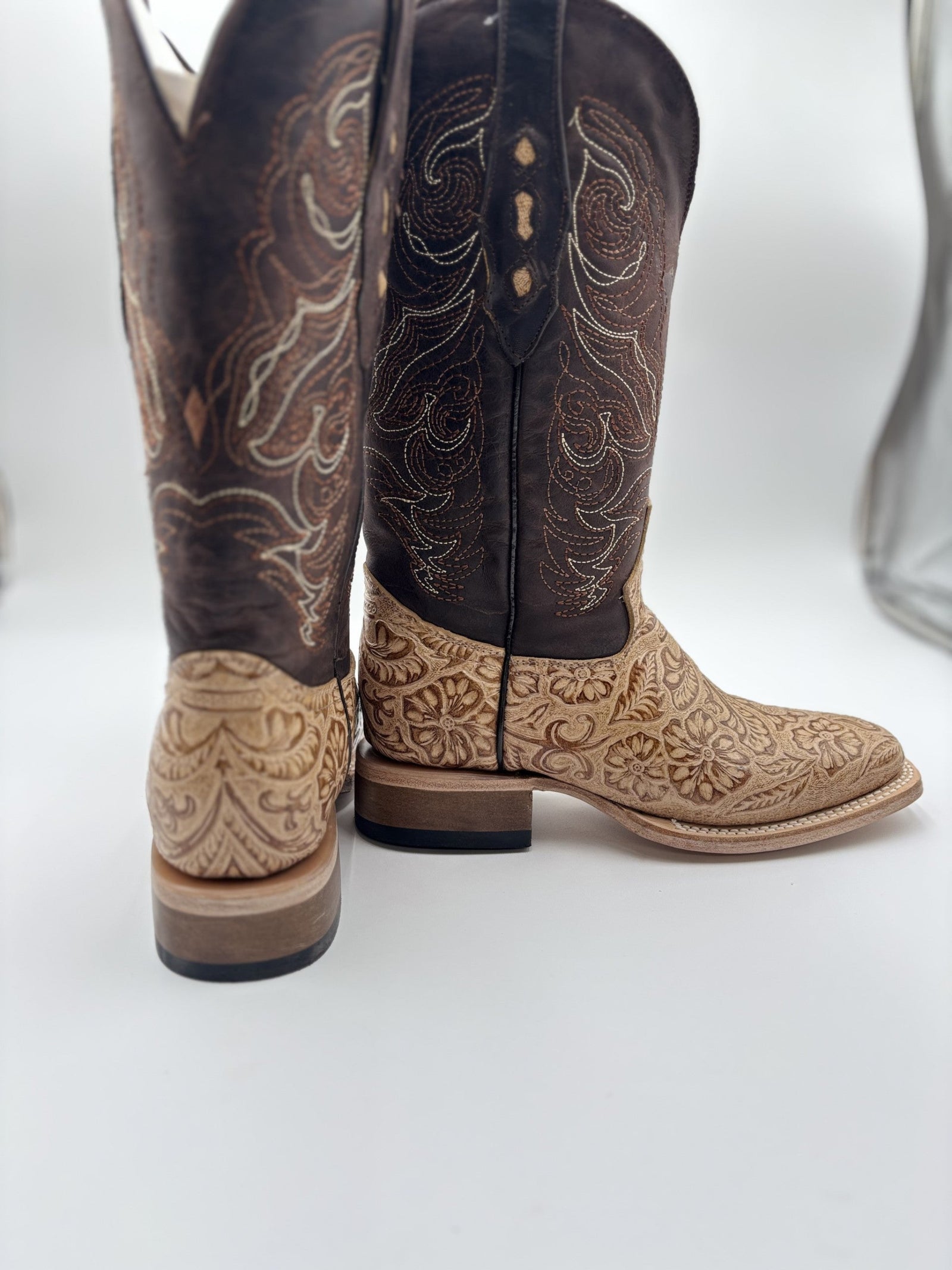 Pair of brown and beige cowboy boots with intricate patterns on a white background