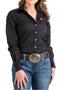 A woman wearing a black long sleeve button front shirt with a left pocket and embroidered logo, button front