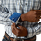 Close-up of a person wearing a plaid shirt with rolled-up sleeves, focusing on the cuff and hands.