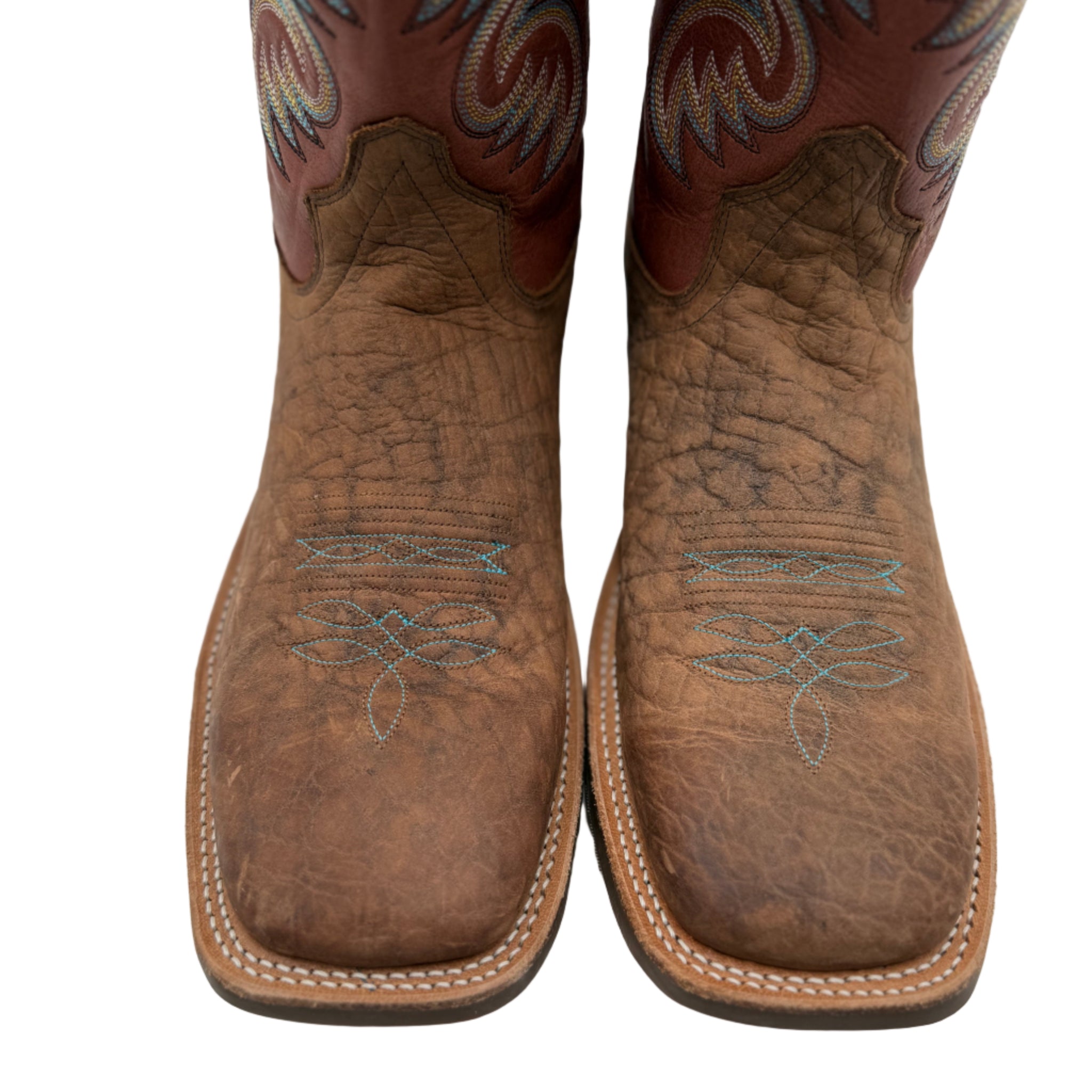 Pair of brown cowboy boots with intricate designs on a white background