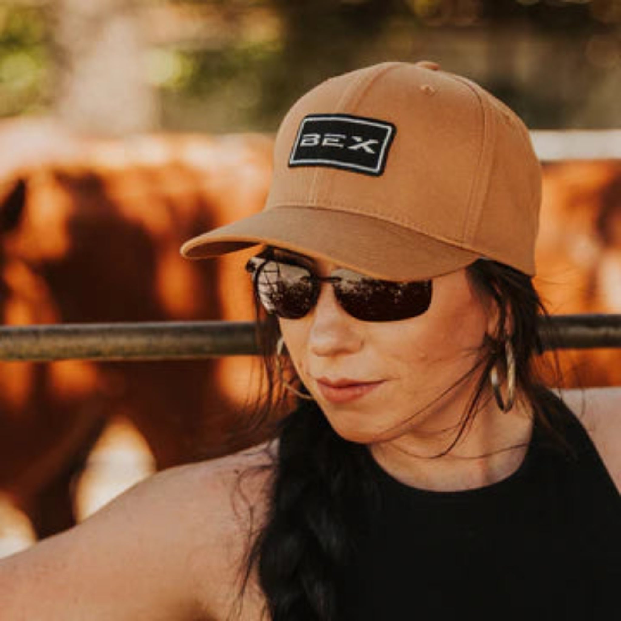 Person wearing a brown cap with a logo and sunglasses