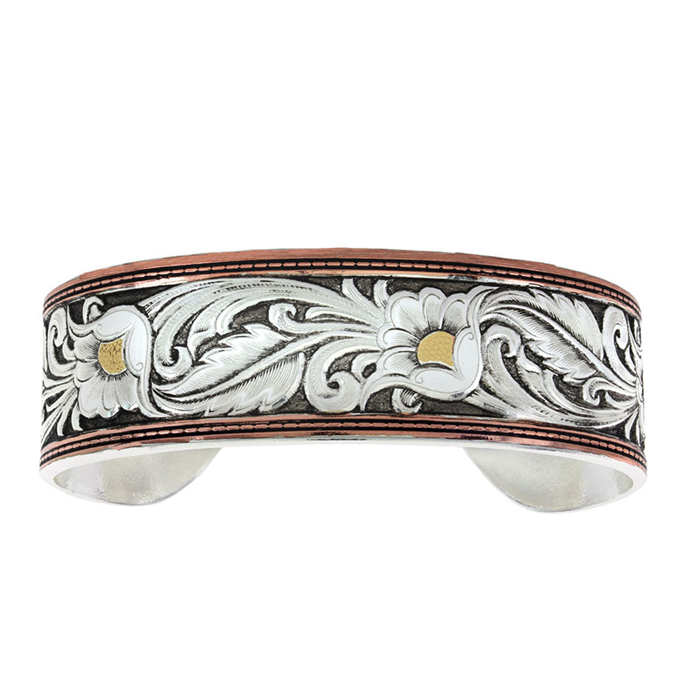 A tri-colored cuff bracelet with a vintage design, featuring a floral and leaf pattern in silver, gold, and copper over a brass base with hand painted black and white details.