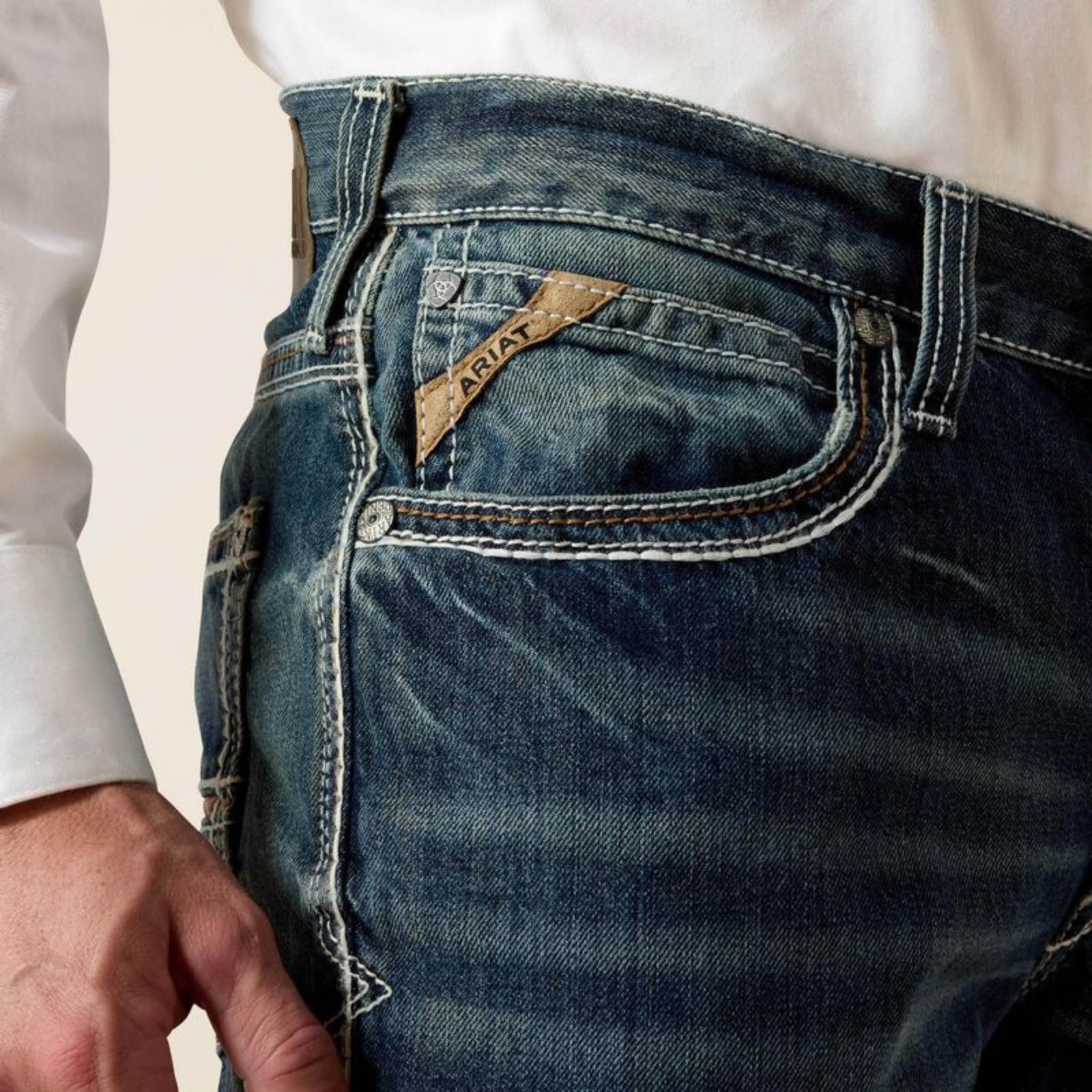 Close-up of a person wearing blue jeans with a brand label.