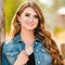 Woman wearing a denim jacket with a blurred natural background