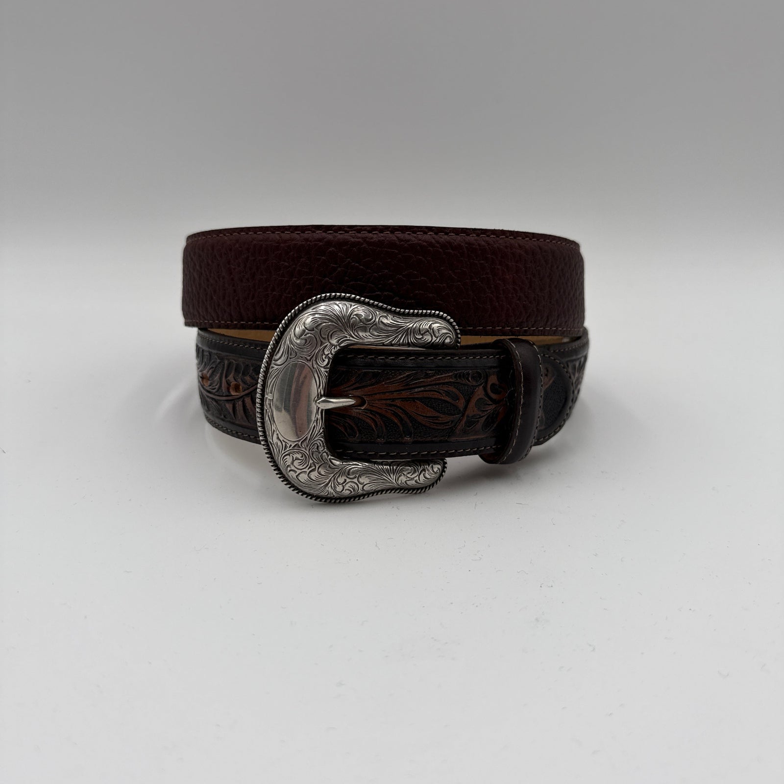Brown belt with silver buckle on a light gray background