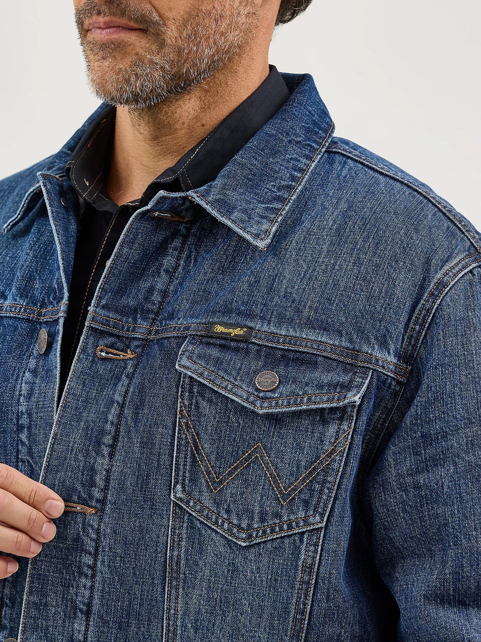 Close-up of a person wearing a blue denim jacket with a brand logo