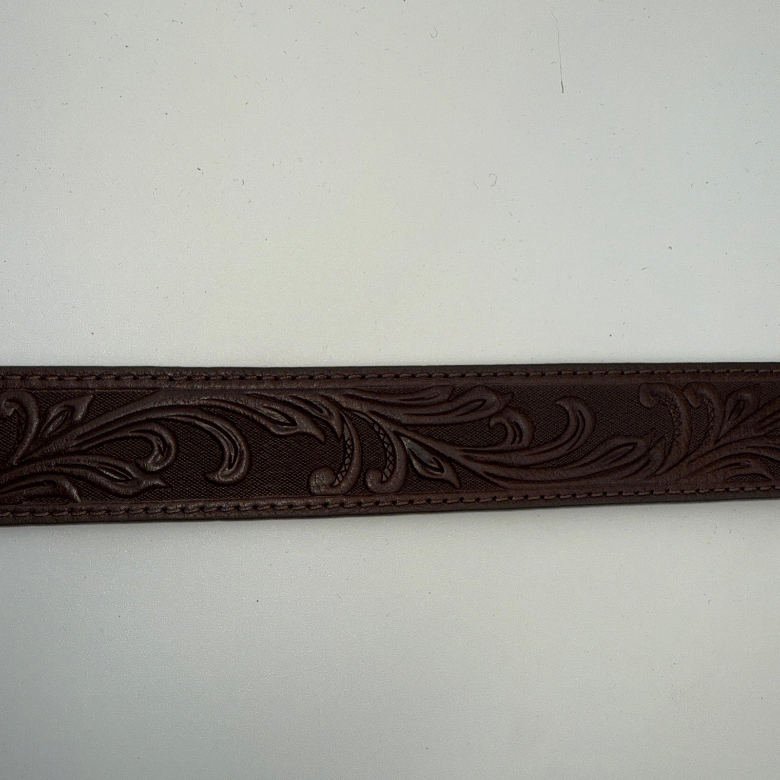 Decorative brown leather strap with intricate patterns on a white background