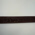 Decorative brown leather strap with intricate patterns on a white background