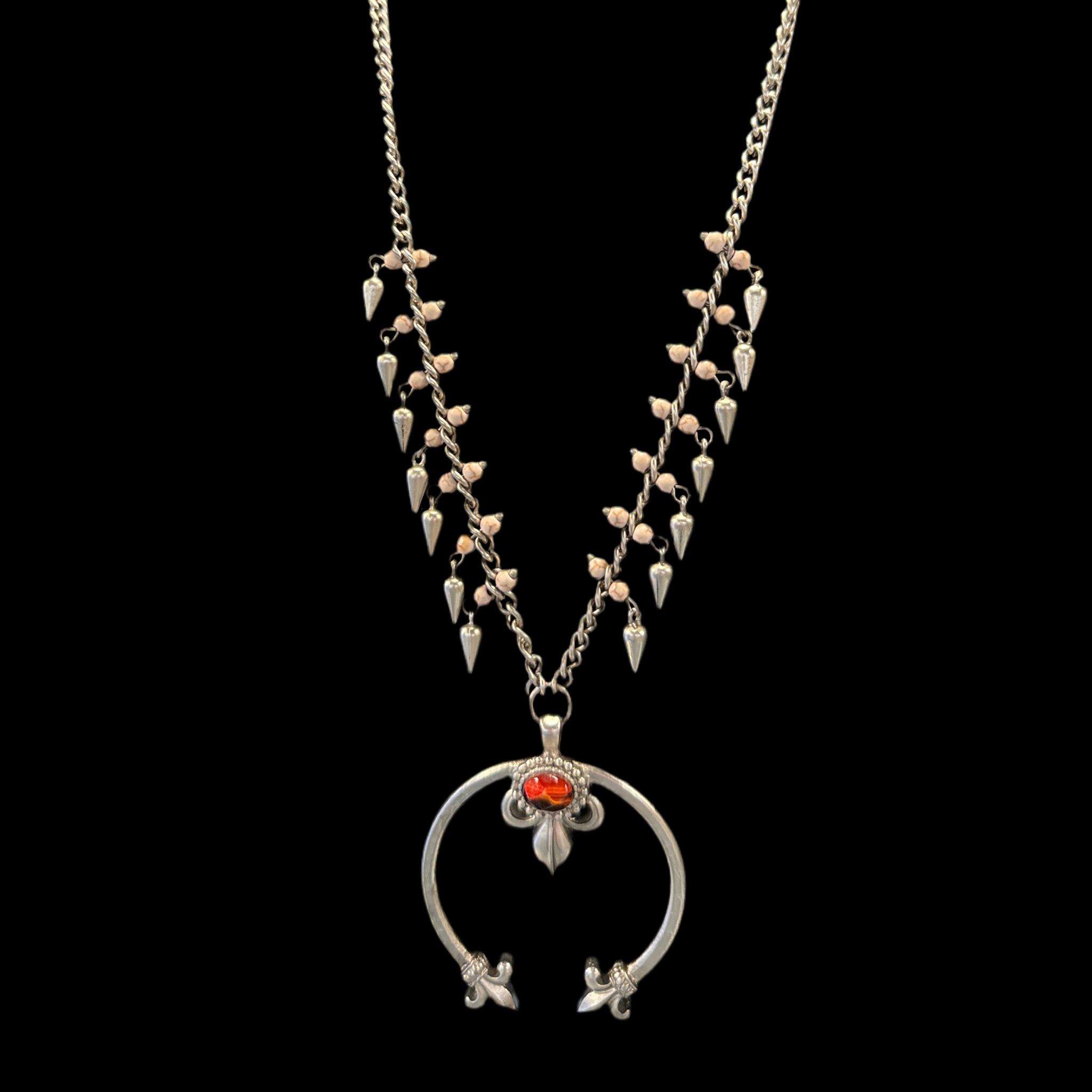 A silver squash blossom necklace with a detailed pattern and a central ornamental circular piece