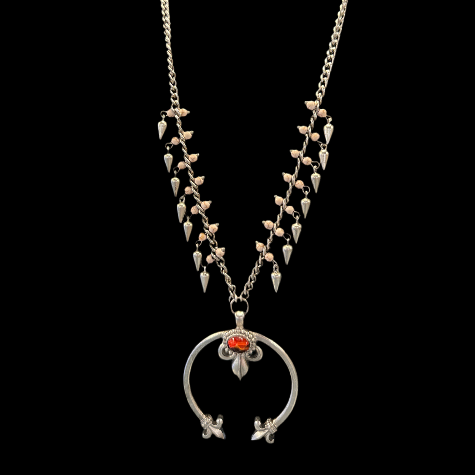 A silver squash blossom necklace with a detailed pattern and a central ornamental circular piece