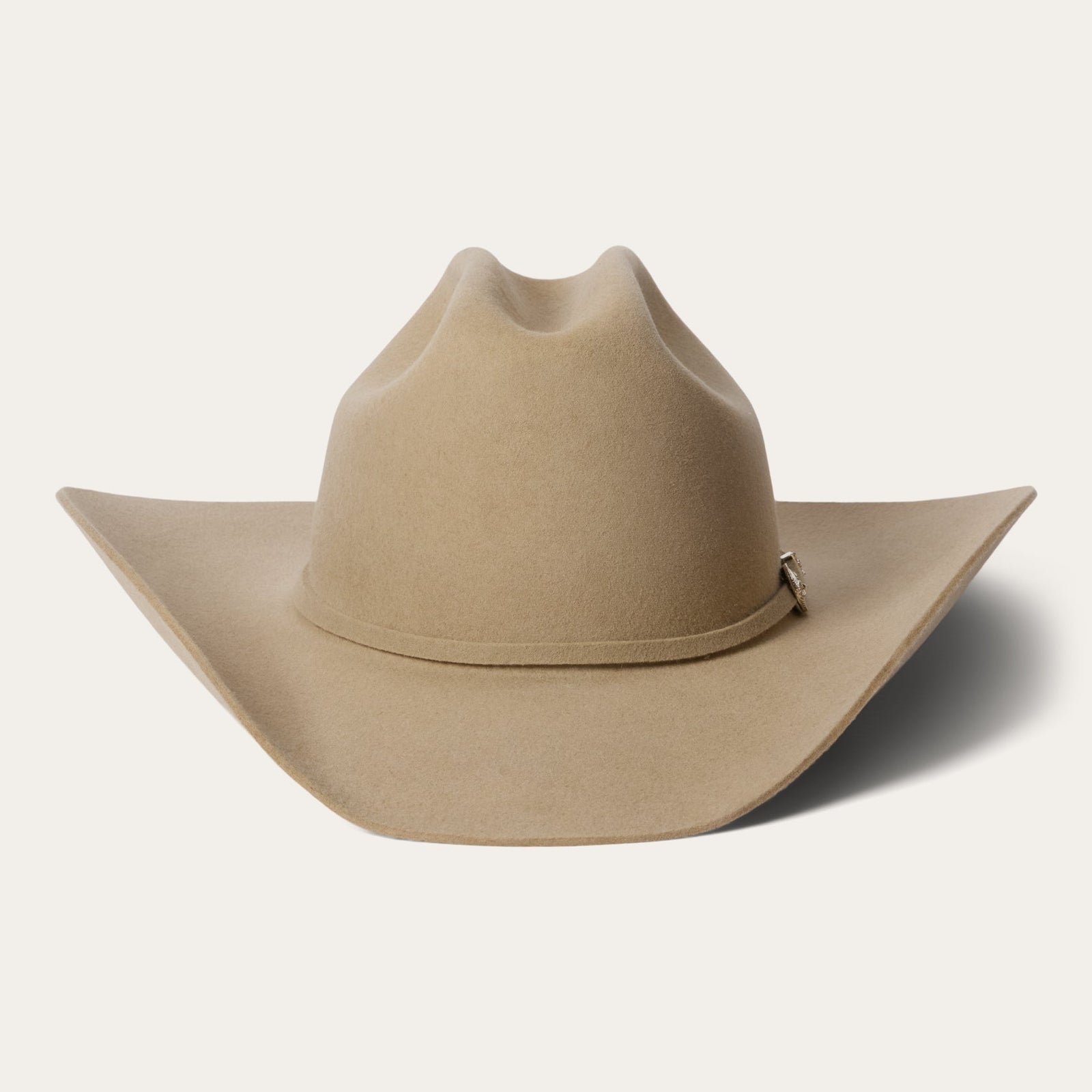 A beige Stetson cowboy hat made of 4X buffalo wool felt with a classic cattleman crease, a 4-inch brim, and a 4 1/2-inch regular oval crown. It features a leather sweatband, satin lining, and a self-matching hat band with a silver-toned buckle set.