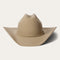 A beige Stetson cowboy hat made of 4X buffalo wool felt with a classic cattleman crease, a 4-inch brim, and a 4 1/2-inch regular oval crown. It features a leather sweatband, satin lining, and a self-matching hat band with a silver-toned buckle set.