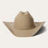 A beige Stetson cowboy hat made of 4X buffalo wool felt with a classic cattleman crease, a 4-inch brim, and a 4 1/2-inch regular oval crown. It features a leather sweatband, satin lining, and a self-matching hat band with a silver-toned buckle set.