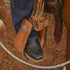 Close-up of a cowboy boot in a stirrup on a horse, with a blurred background.