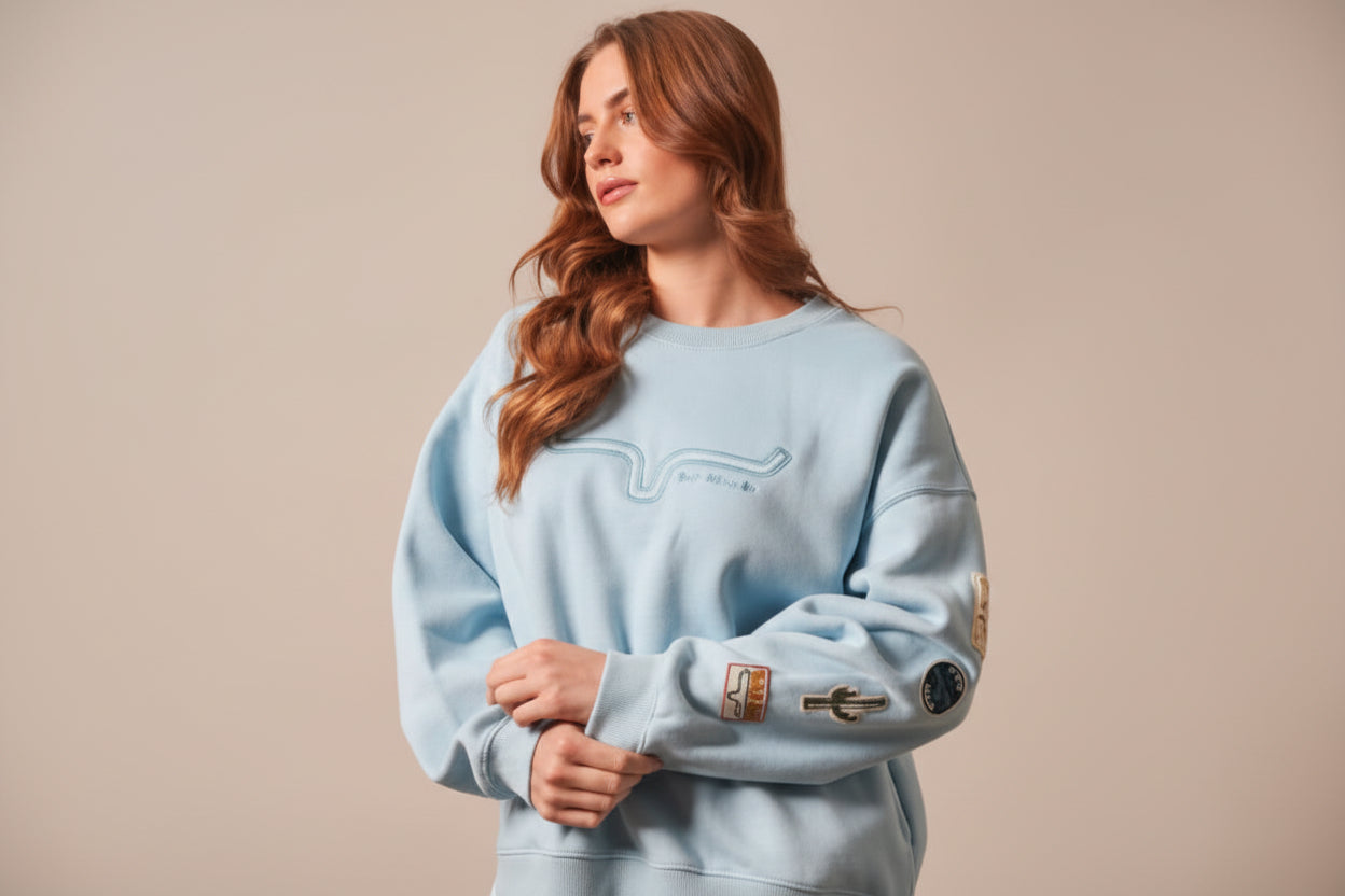 Ladies light blue sweatshirt with the Kimes brand logo and appliqued patches on left sleeve