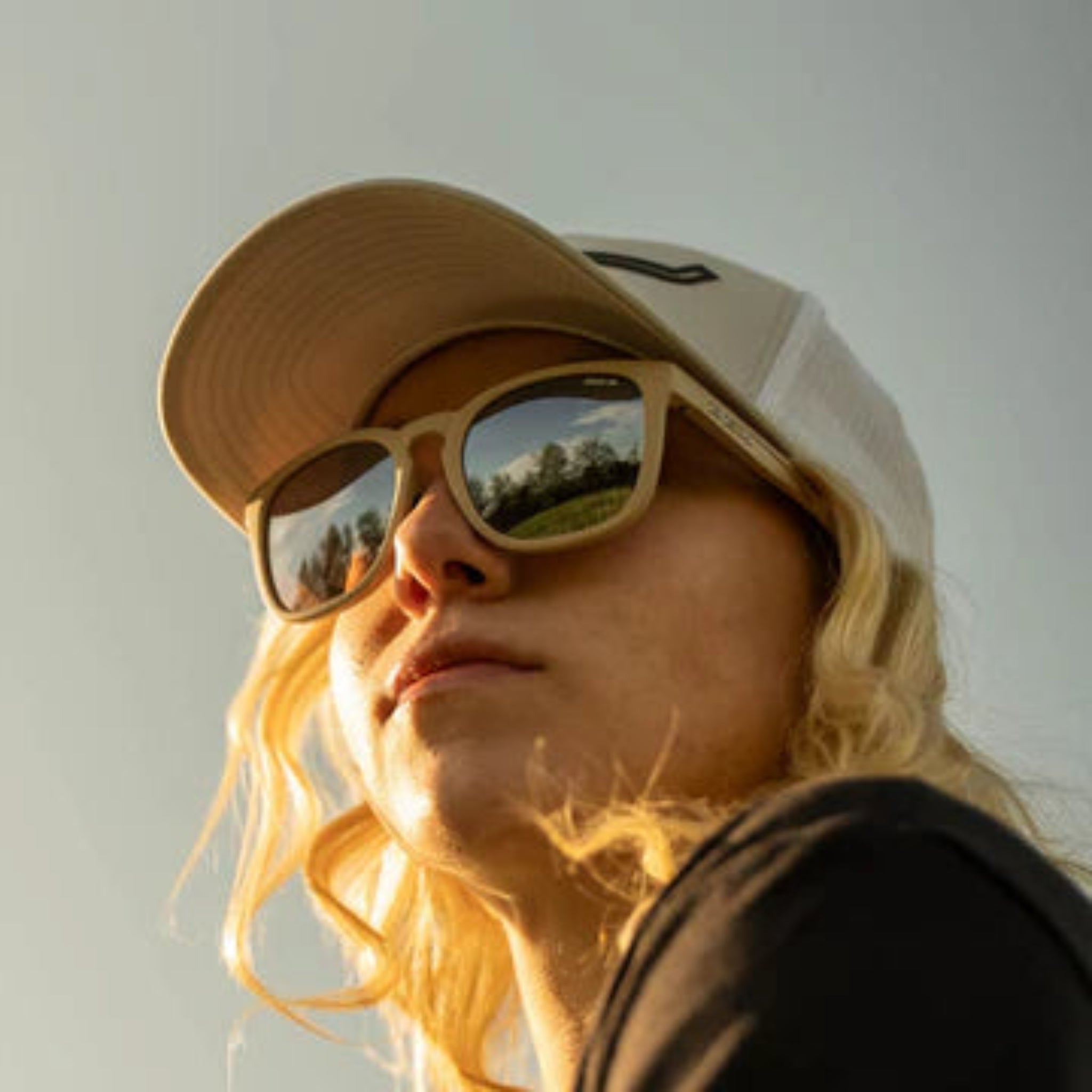 Person wearing a ball cap and sunglasses with a neutral background